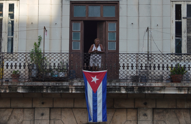 Una mujer en un balcón con una bandera cubana en el centro de La Habana, el 11 de julio de 2022. REUTERS/Alexandre Meneghini.