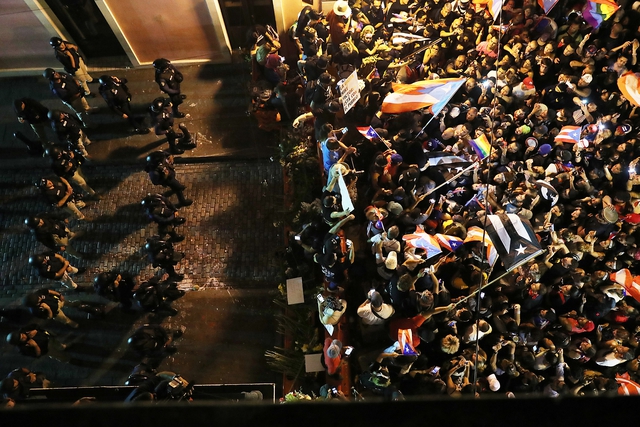 Protesters demonstrate near a police barricade on a street leading to the governor's mansion in Old San Juan, Puerto Rico. 24 July 2019. (Photo by Joe Raedle/Getty Images)