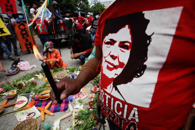 A demonstrator holds a candle at a protest demanding justice for Berta Cáceres outside the Supreme Court during trial of Roberto David Castillo. June 2022, REUTERS/Fredy Rodriguez.